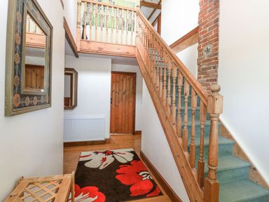A hallway with stairs and a mirror at Lakeside Barn Aylsham