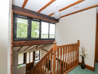 A staircase with wooden railings and windows at Lakeside Barn Aylsham