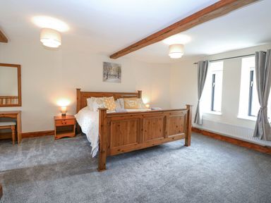 A bedroom with a wooden bed and nightstand at Lakeside Barn Aylsham
