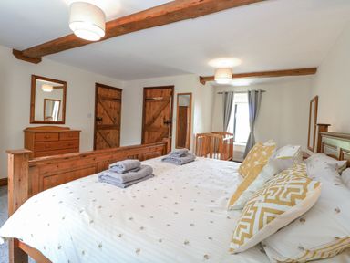 A bedroom with a bed and dresser at Lakeside Barn Aylsham