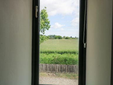 A view from a window of a field and trees at Lakeside Barn Aylsham