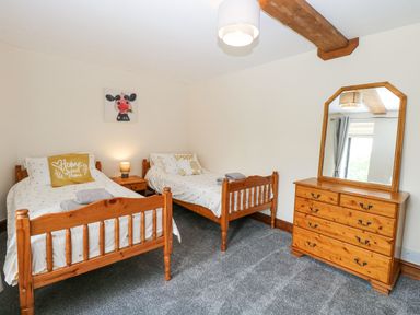 A bedroom with twin beds and a chest of drawers at Lakeside Barn in Aylsham