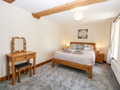 A bedroom with a bed, nightstands and a vanity at Lakeside Barn Aylsham