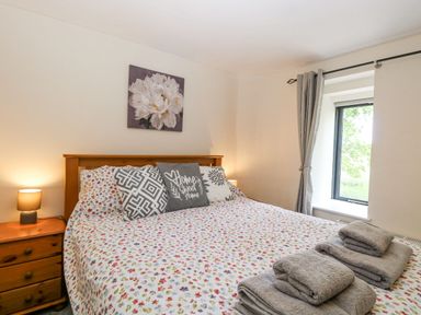 A bedroom with a bed and a window at Lakeside Barn Aylsham