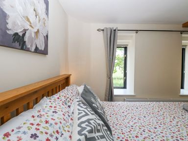 A bedroom with a bed and windows at Lakeside Barn Aylsham