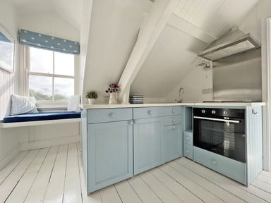 A kitchen with cabinets and a window at Trenare in Truro