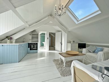 A living room with a kitchen area and a table at Trenare in Truro