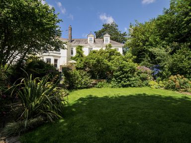 A garden with a house in the background at Trenare in Truro