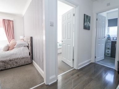 A hallway with open white doors leading to bedrooms and a bathroom at 67 Pendre Avenue Prestatyn