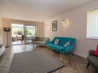 A living room with two sofas a glass door leading to a dining area and a patterned rug at Hillside in Bishops Cleeve