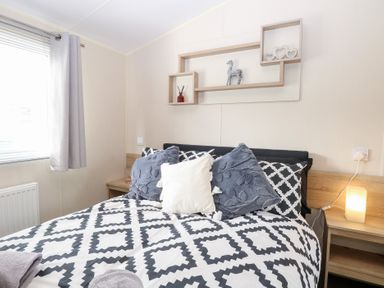 A bedroom with a bed and decorative shelf at Number 34 Foxburrow Hang Great Yarmouth