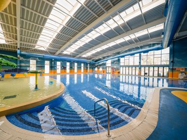 An indoor swimming pool with a small shallow play area and large windows at Starlight Skylight - Billing Aquadrome Holiday Park
