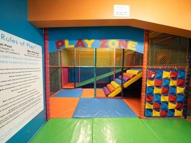 An indoor children's play area with padded floor mats colorful climbing structures and a sign with rules at Billing Aquadrome Holiday Park