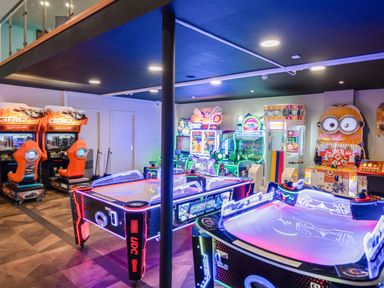 An arcade room with air hockey tables racing game machines and various arcade games at Starlight Skylight - Billing Aquadrome Holiday Park