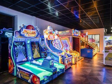 An indoor arcade room with bowling and skee-ball arcade machines at Starlight Skylight - Billing Aquadrome Holiday Park