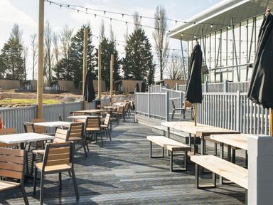 An outdoor seating area with wooden tables and chairs and closed umbrellas at Starlight Skylight Billing Aquadrome in Billing Aquadrome Holiday Park