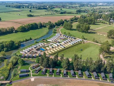 An aerial view of a caravan park with rows of caravans and lodges near a river in a rural landscape at Aquadrome Abode Billing Aquadrome