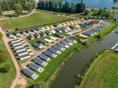 An aerial view of a holiday park with rows of cabins near a water body and green fields at Lakeside Lullaby in Billing Aquadrome Holiday Park