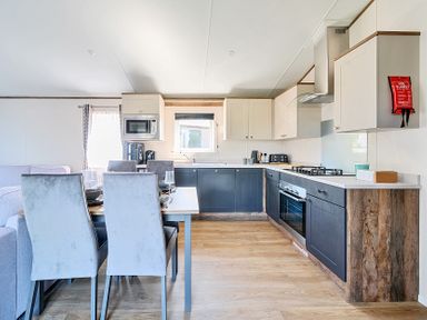 A kitchen and dining area with table and chairs and kitchen appliances at Lakeside Lullaby - Billing Aquadrome in Billing Aquadrome Holiday Park