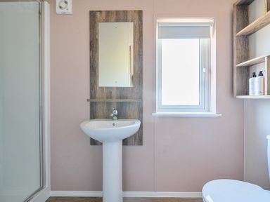 A bathroom with a pedestal sink mirror window shelves and a shower at Lakeside Lullaby - Billing Aquadrome in Billing Aquadrome Holiday Park