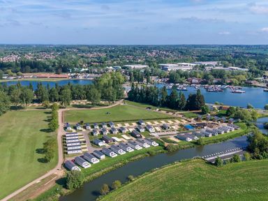 An aerial view of a holiday park with rows of caravans near a river and a marina with boats in Billing Aquadrome Holiday Park