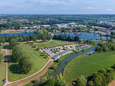 An aerial view of a holiday park with rows of caravans near a river and a lake with boats at Moonlit Skylight - Billing Aquadrome in Billing Aquadrome Holiday Park