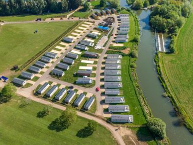 Aerial view of a holiday park with rows of mobile homes near a river at Moonlit Skylight - Billing Aquadrome in Billing Aquadrome Holiday Park