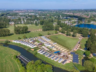 An aerial view of a holiday park with rows of cabins along a river and large green fields at Billing Aquadrome Holiday Park