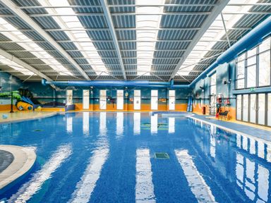 An indoor swimming pool with water slides windows and safety equipment at Moonlit Skylight - Billing Aquadrome in Billing Aquadrome Holiday Park