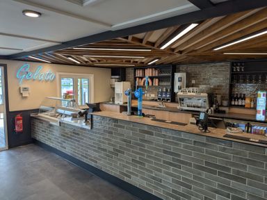An ice cream and coffee counter with a gelato display case taps and coffee machine at Moonlit Skylight - Billing Aquadrome