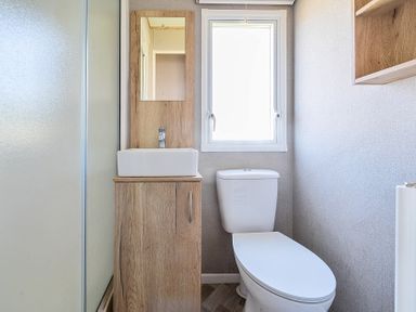 A small bathroom with a toilet sink cabinet and a window at Willowbrook Hideaway - Billing Aquadrome Holiday Park
