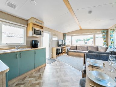 An open plan living area with kitchen, dining table, sofa, and television at Brookside Bliss - Billing Aquadrome in Billing Aquadrome Holiday Park