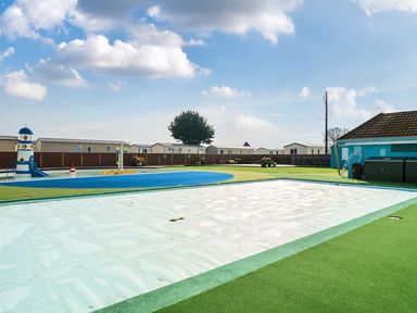 An outdoor recreation area with playground equipment and a swimming pool cover at Mariner's Meadow - Hayling Island