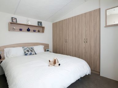 A bedroom with a bed and wardrobe at Mariner's Meadow - Hayling Island