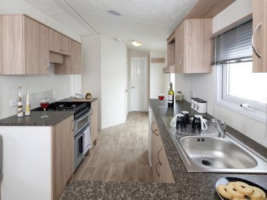 A kitchen with cabinets and a stove at Mariner's Meadow - Hayling Island Holiday Park