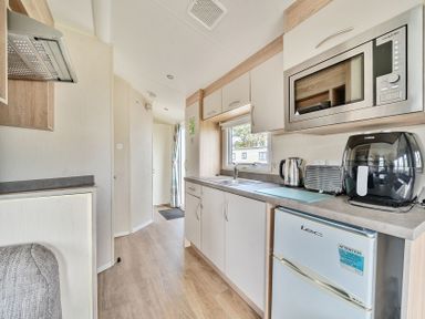 A kitchen area with microwave kettle toaster air fryer and fridge at Golden Dune - Hayling Island in Hayling Island Holiday Park