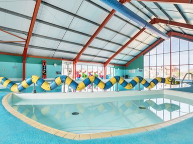 An indoor pool with a colorful slide at Golden Dune - Hayling Island