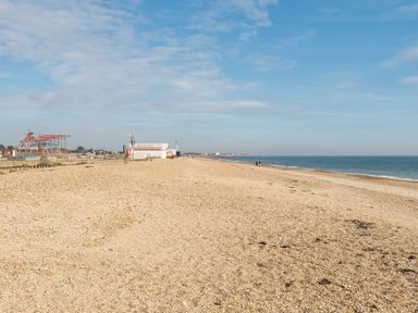 A beach with a hut and people walking at Golden Dune - Hayling Island