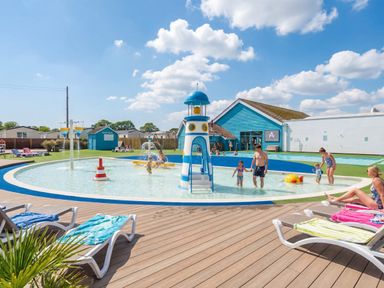 An outdoor swimming area with a pool and water slide at Golden Dune - Hayling Island
