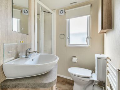 A bathroom with a sink countertop toilet shower and window at The Lookout - Hayling Island in Hayling Island Holiday Park