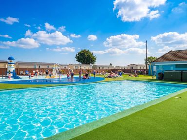 An outdoor pool area with a fountain and children playing at Sunset Sands - Hayling Island