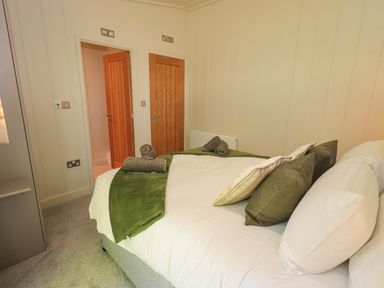 A bedroom with a bed with pillows and towels and two wooden doors Kingfisher Lodge Gargrave