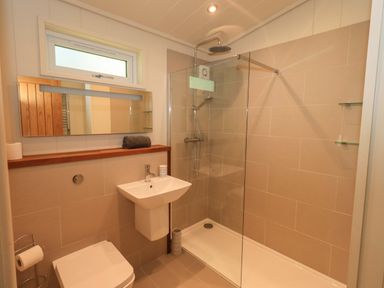 A bathroom with a toilet sink and a walk in shower at Kingfisher Lodge in Gargrave