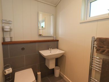 A bathroom with a toilet sink mirror towel rack and window at Kingfisher Lodge in Gargrave