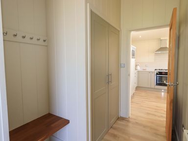 A hallway with a bench and coat hooks leading to a kitchen with an oven and range hood at Kingfisher Lodge in Gargrave