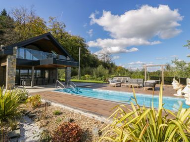 An outdoor area with a swimming pool and seating at Forest Lodge Pontyclun
