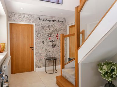 A hallway with a staircase and signed wall at Forest Lodge in Pontyclun