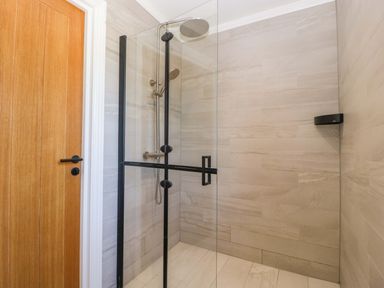 A shower with glass door and wall tiles at Forest Lodge in Pontyclun