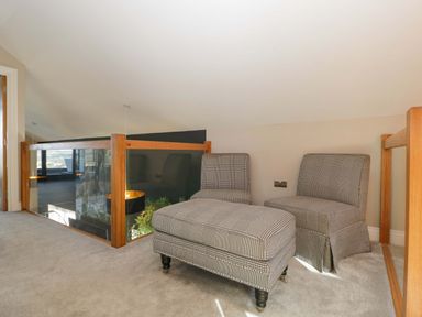 A loft area with two checkered chairs and an ottoman at Forest Lodge in Pontyclun