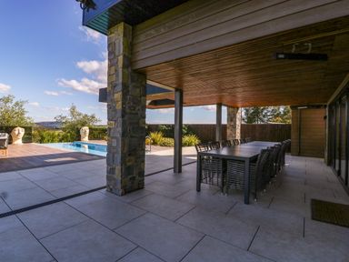 An outdoor patio with a pool and dining table at Forest Lodge in Pontyclun